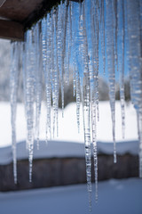 Cold temperatures causing icicles in winter . Blurred Background behind the icicles
