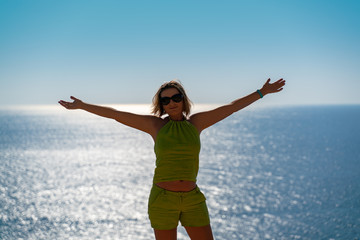 Fototapeta na wymiar girl with outstretched arms on a background of blue sea water