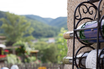 Fototapeta na wymiar Two wine bottles in wrought iron carrier at house wall in Dürnstein, Lower Austria, and view at Wachau region