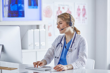 Portrait of a happy smiling young doctor in headset in office