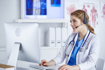 Portrait of a happy smiling young doctor in headset in office