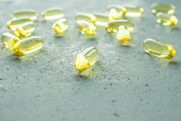 yellow transparent oval capsule vitamins pills on gray concrete background