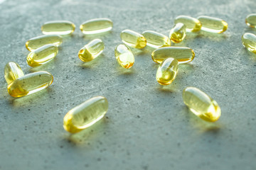 yellow transparent oval capsule vitamins pills on gray concrete background