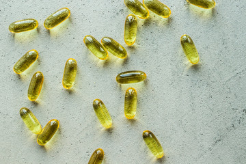 yellow transparent oval capsule vitamins pills on gray concrete background