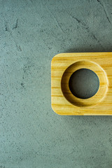 wooden stand with one hole in the middle on the right side on a gray concrete background