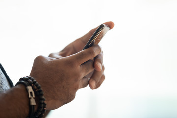 Close up image african american mans hands holding smartphone.