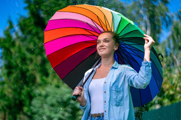 Happy cheerful woman with colored umbrella during the summer rain