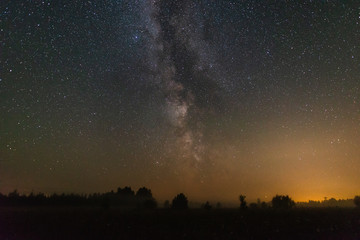 Starry sky with milky way over the field with fog summer night