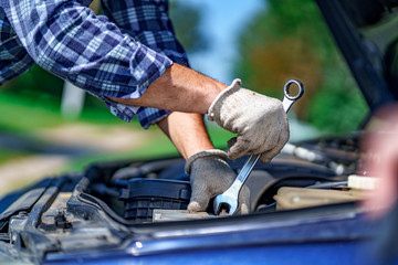 Auto mechanic repairing a car engine with a wrench