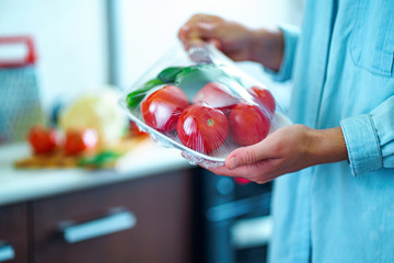 Woman packaged fresh vegetables using food film for food storage in fridge