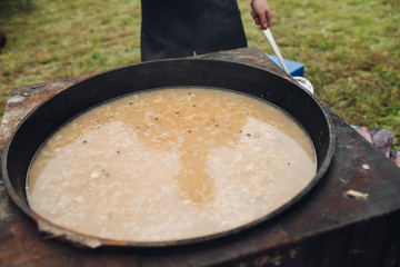 Closeup of delicious soup with potatos and carrots. Selective focus of spoon with tasty healthy dinner during picnic. Concept of cooking, food and cuisine.