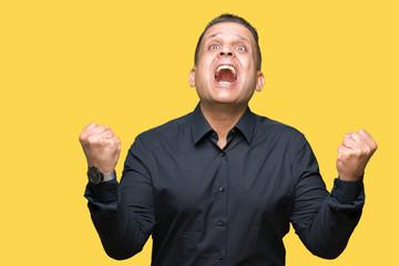 Fototapeta premium Handsome middle age arab business man over isolated background celebrating surprised and amazed for success with arms raised and open eyes. Winner concept.