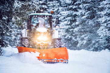 Snow plow truck clearing road after winter snowstorm blizzard for vehicle access