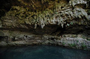 Stalactites and blue pool of undeground lake.