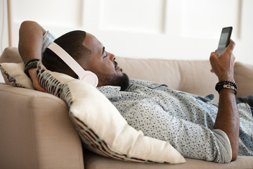 African american happy man relaxing on pillow on comfy sofa.
