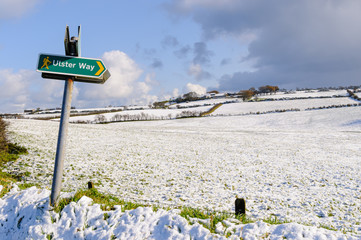 Ulster Way sign with snow on fields in background