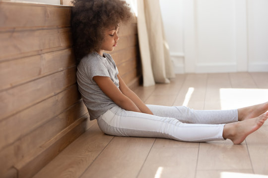 Upset Black Cute Kid Girl Sitting Alone On Floor.