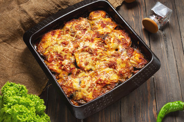Baked eggplant with cheese on a wooden table. Parmigiana melanzane. Italian cuisine.