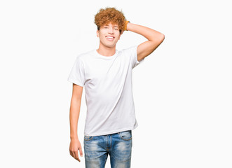 Fototapeta premium Young handsome man with afro hair wearing casual white t-shirt Smiling confident touching hair with hand up gesture, posing attractive