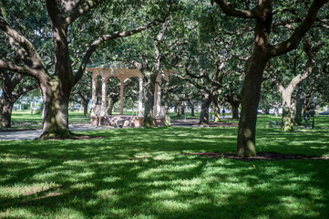 Sun-dappled view of classic Southern gazebo set amongst a canopy of oak trees in White Point Garden park in the Battery, Charleston, South Carolina, USA 