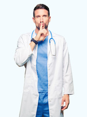 Handsome doctor man wearing medical uniform over isolated background asking to be quiet with finger...