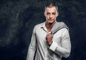 Portrait of handsome intellegent man in suit and white shirt at dark photo studio.