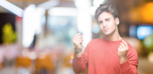 Young handsome man over isolated background Doing money gesture with hand, asking for salary payment, millionaire business