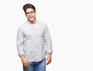 Fototapeta premium Young handsome man wearing glasses over isolated background sticking tongue out happy with funny expression. Emotion concept.