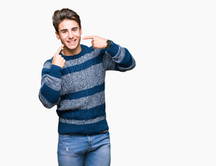 Young handsome man over isolated background smiling confident showing and pointing with fingers teeth and mouth. Health concept.