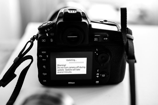 PARIS, FRANCE - JAN 31, 2018: Black and white Nikon DSLR Camera Professional updating firmware with message on the screen: Do not turn camera off during update
