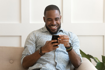 Addicted happy smiling african american guy using mobile phone.