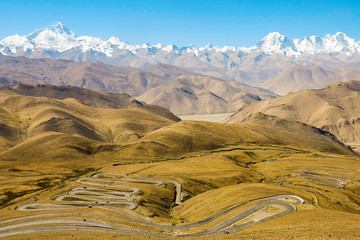 Picturesque view of a winding mountain road leading to the snowy Himalayas.
