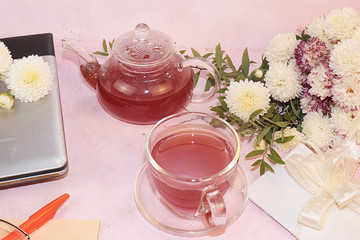 Computer, autumn flowers, a blank notebook with pen and a cup of flower tea on the desktop, top view, flat lay. A break at work in the office in comfortable conditions, the cosiness of our home, 