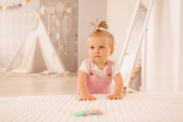 Fototapeta premium baby girl in the nursery playing,bright children's room, textiles for children's room