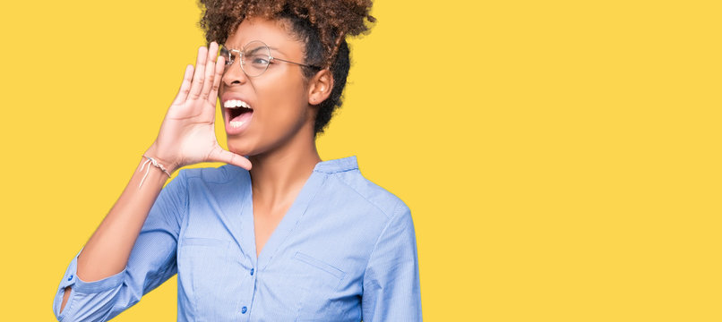 Beautiful young african american business woman over isolated background shouting and screaming loud to side with hand on mouth. Communication concept.