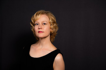 Studio portrait of a woman with a thoughtful, serious expression against a dark background.