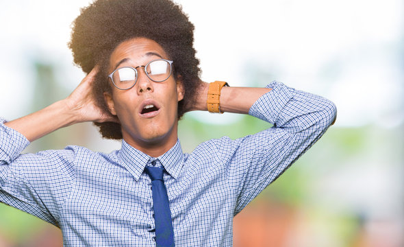 Young african american business man with afro hair wearing glasses Crazy and scared with hands on head, afraid and surprised of shock with open mouth