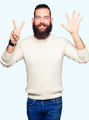 Naklejka premium Young hipster man wearing winter sweater showing and pointing up with fingers number seven while smiling confident and happy.
