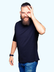 Fototapeta premium Young blond man wearing casual t-shirt doing ok gesture with hand smiling, eye looking through fingers with happy face.