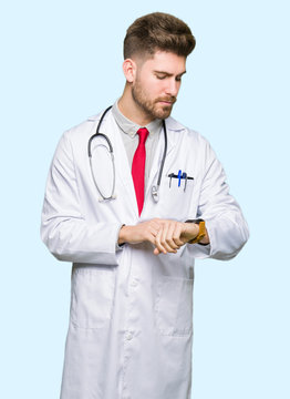 Young handsome doctor man wearing medical coat Checking the time on wrist watch, relaxed and confident