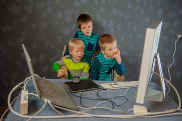 Funny kids watch educational program on computer and learn to read and count. Boys repeat speaker...