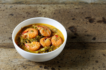 Coconut Milk Curry with young Tamarind Leaves and shrimp in bowl on wood table.Thai traditional food