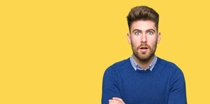 Young handsome bussines man afraid and shocked with surprise expression, fear and excited face.