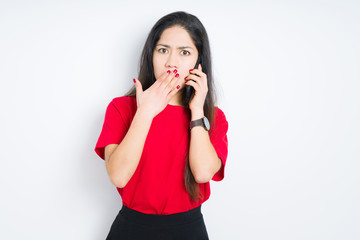 Young brunette woman talking on smartphone over isolated background cover mouth with hand shocked with shame for mistake, expression of fear, scared in silence, secret concept