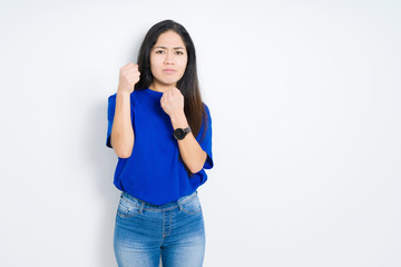 Beautiful brunette woman over isolated background Ready to fight with fist defense gesture, angry and upset face, afraid of problem