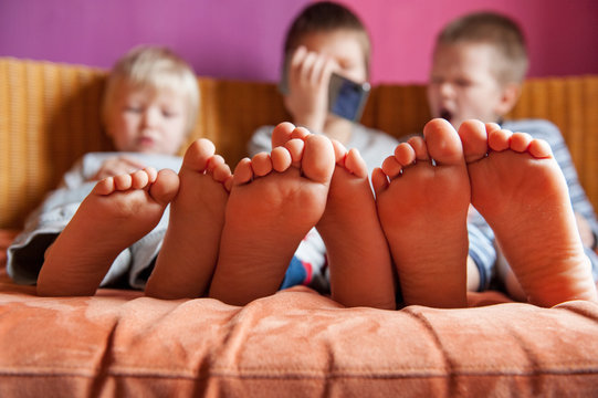 Funny kids lay on sofa to play computer games on smartphone. Parents gave the children a new phone for Christmas. Modern children are well aware of latest technology. Brothers are happy together