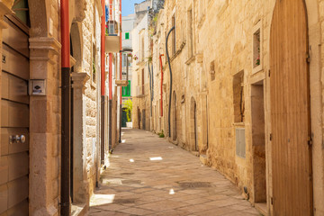 Fototapeta premium Italy, Apulia, Metropolitan City of Bari, Molfetta. Small cobblestone street and stone residential buildings.
