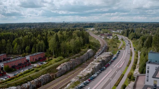 An AERIAL VIEW TRACKING SHOT of a train entering a city surrounded by a forest.