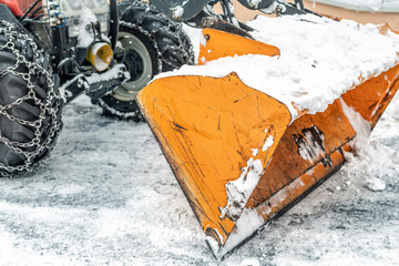 Close-up snowplow of big tractor machine removing and cleaning snow after storm on icy road or city...