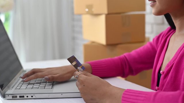 Beautiful woman's hand typing number of a credit card on laptop computer for buying online internet shopping concept